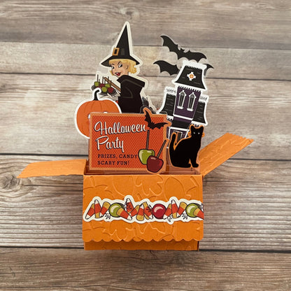 Halloween-themed pop-up card with witch, pumpkin, and castle on a wooden background