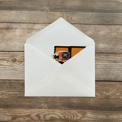 White envelope with a card featuring a black cat design on a wooden surface