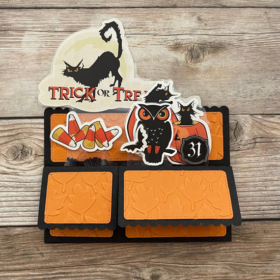 Halloween-themed card with owl, candy corn, and black cat design on a wooden background