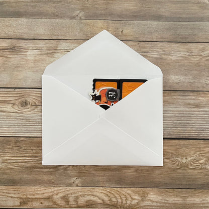 White envelope with a card featuring a black cat design on a wooden surface