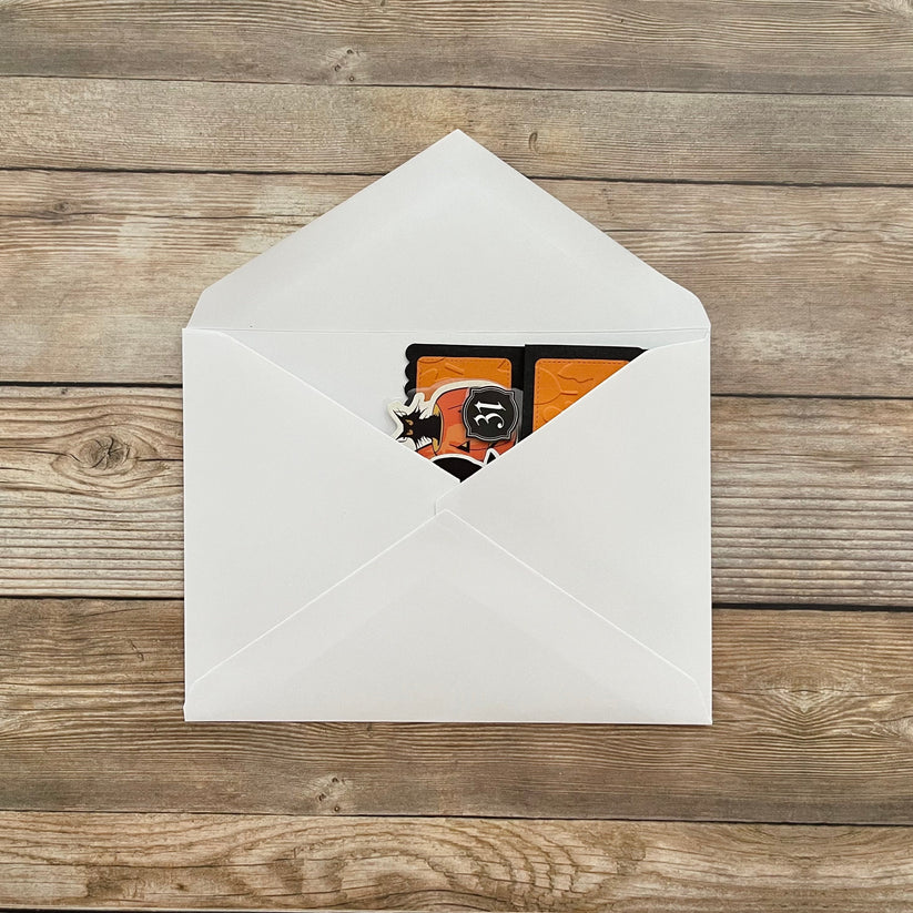 White envelope with a card featuring a black cat design on a wooden surface