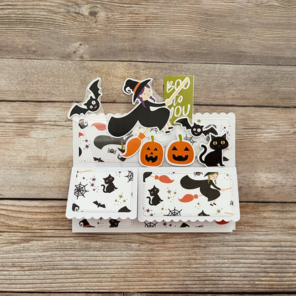 Set of Halloween-themed cards with witches, cats, and pumpkins on a wooden surface.