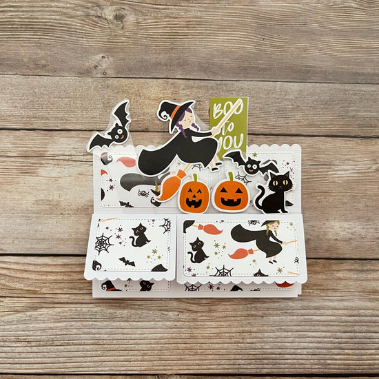 Set of Halloween-themed cards with witches, cats, and pumpkins on a wooden surface.