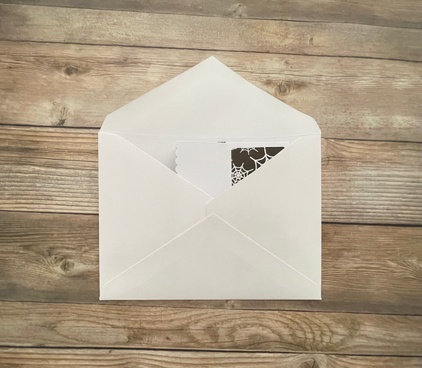 White envelope with a decorative cutout on a wooden surface