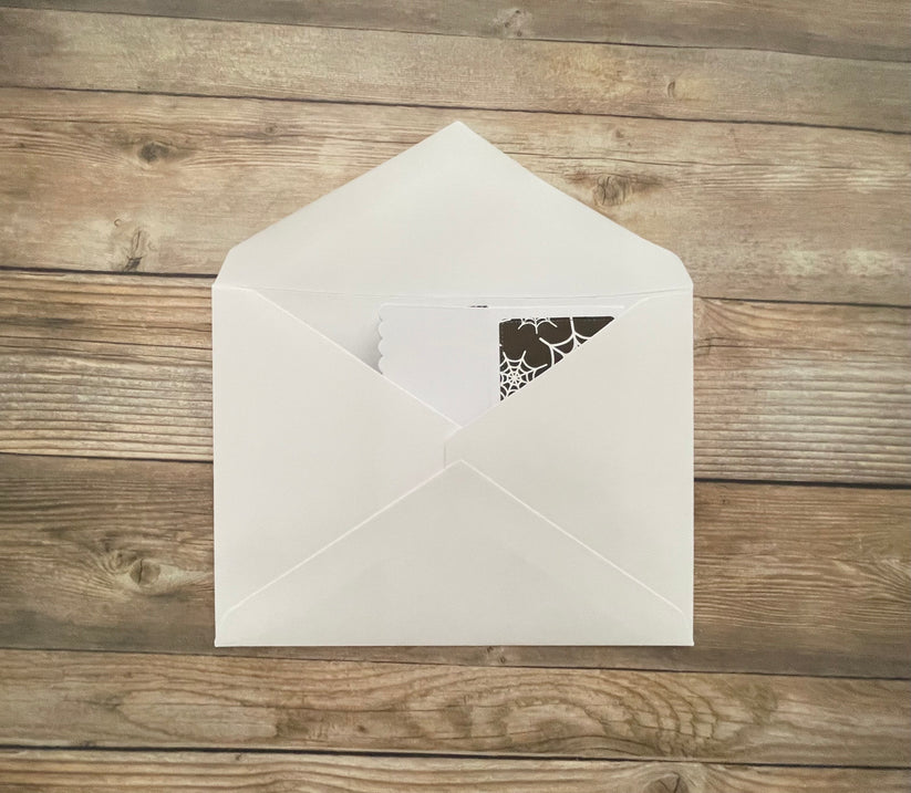 White envelope with a decorative cutout on a wooden surface