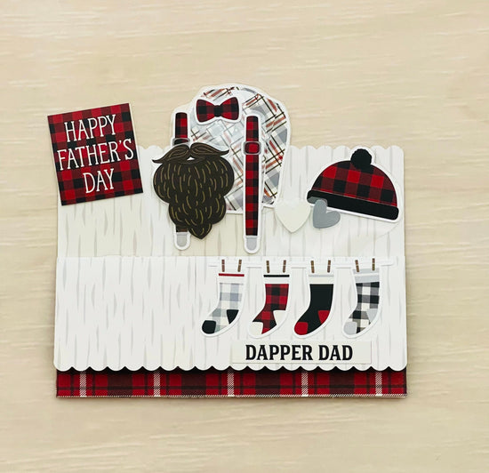 Father's Day pop-up card with plaid patterns, beard, hat, and socks on a wooden surface