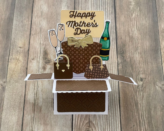 Pop-up card with handbags, a bottle, and 'Happy Mother's Day' text on a wooden surface