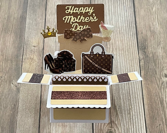 Card with 'Happy Mother's Day' text, high heels, handbag, and tiara on a wooden surface