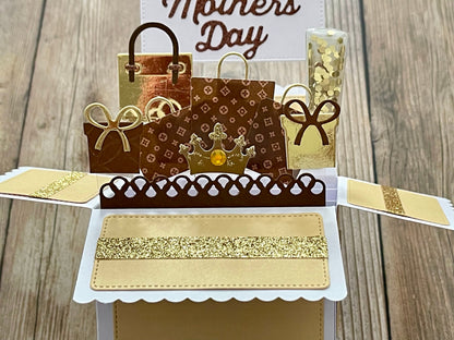 Pop-up card with shopping bags and 'Mother's Day' text on a wooden background
