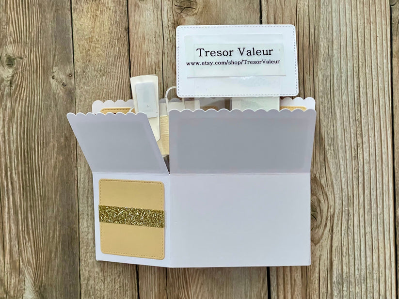 Open white cardholder with gold card and Tresor Valeur branded card on a wooden surface