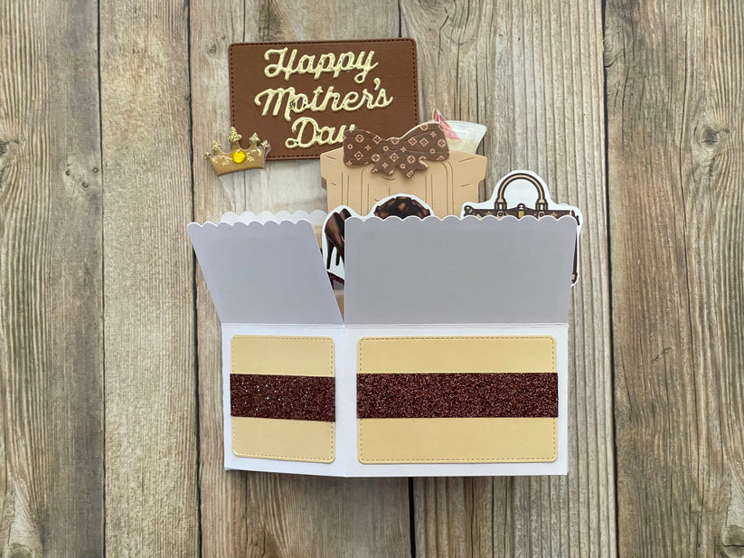 Card with cake design and 'Happy Mother's Day' sign on a wooden background