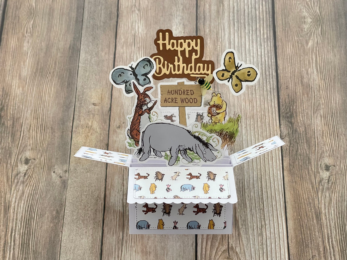 Pop-up birthday card with animal illustrations on a wooden surface