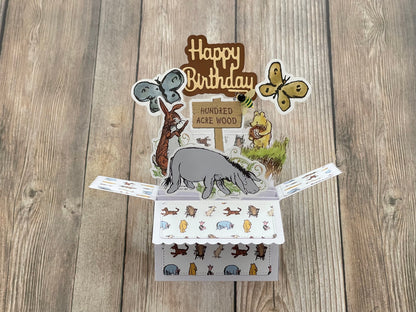 Pop-up birthday card with animal illustrations on a wooden surface