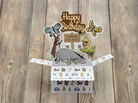 Pop-up birthday card with animal illustrations on a wooden surface