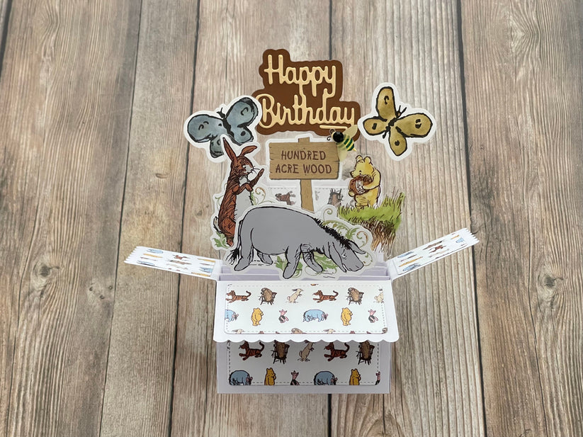 Pop-up birthday card with animal illustrations on a wooden surface