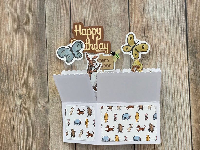 Open card with birthday decorations and illustrations on a wooden surface