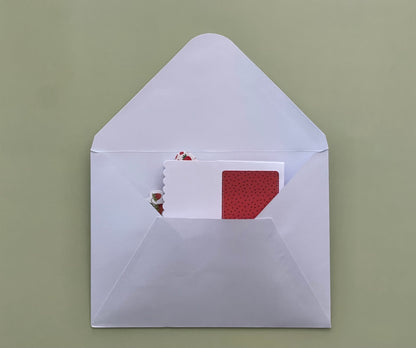 White envelope with a red and white card on a green background