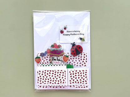 Packaged folded pop up card with strawberry-themed design on a light green background
