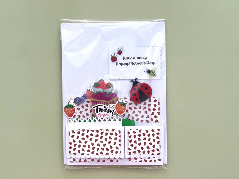 Packaged folded pop up card with strawberry-themed design on a light green background