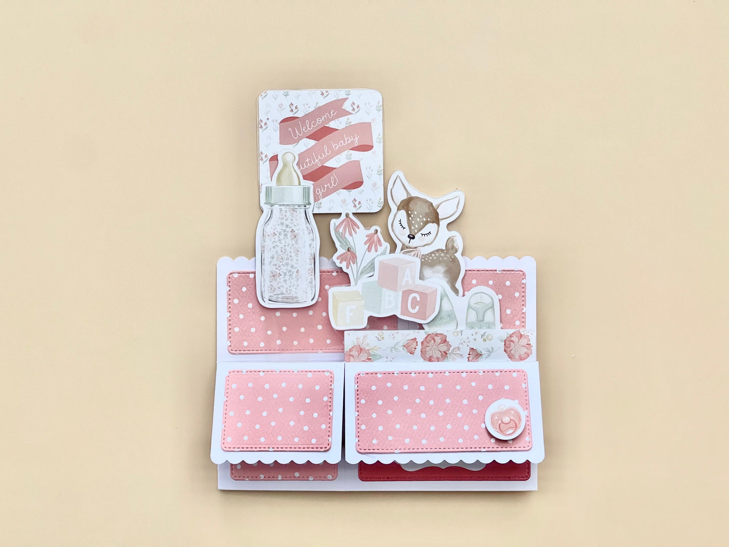 Folded box pop-up baby card in pink tones.