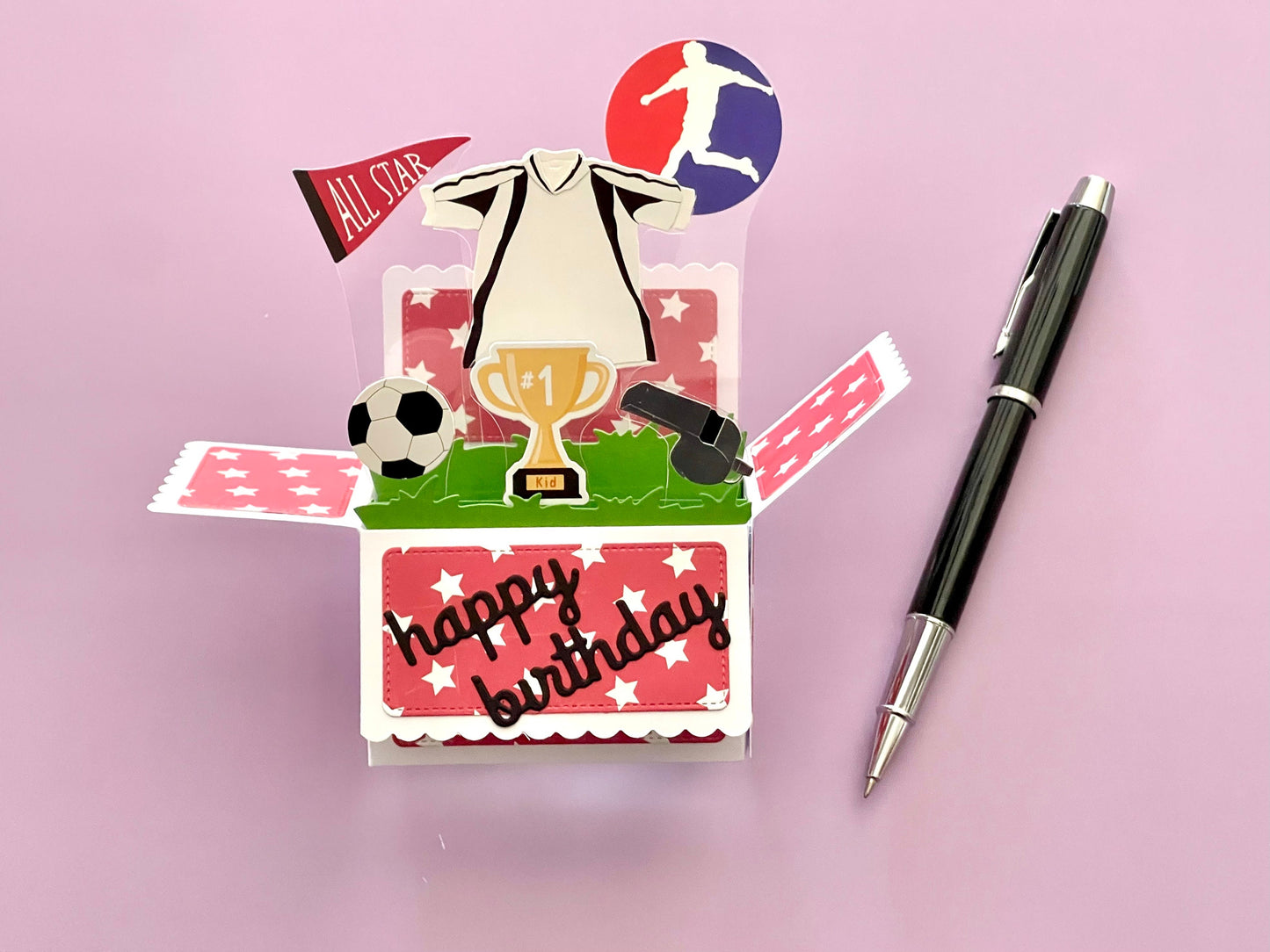 Soccer-themed birthday card with a pen on a pink background