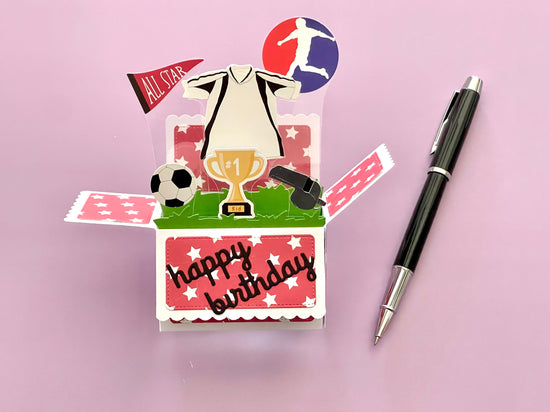 Soccer-themed birthday card with a pen on a pink background