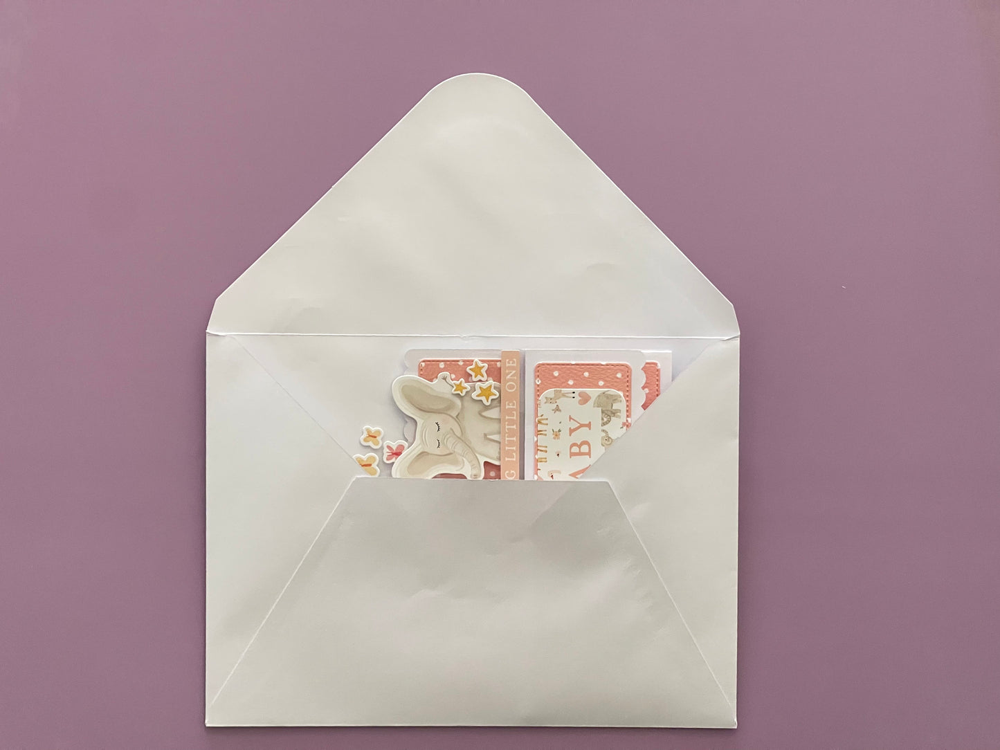 White envelope with a card featuring a cat illustration on a purple background