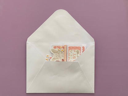 White envelope with a card featuring a cat illustration on a purple background