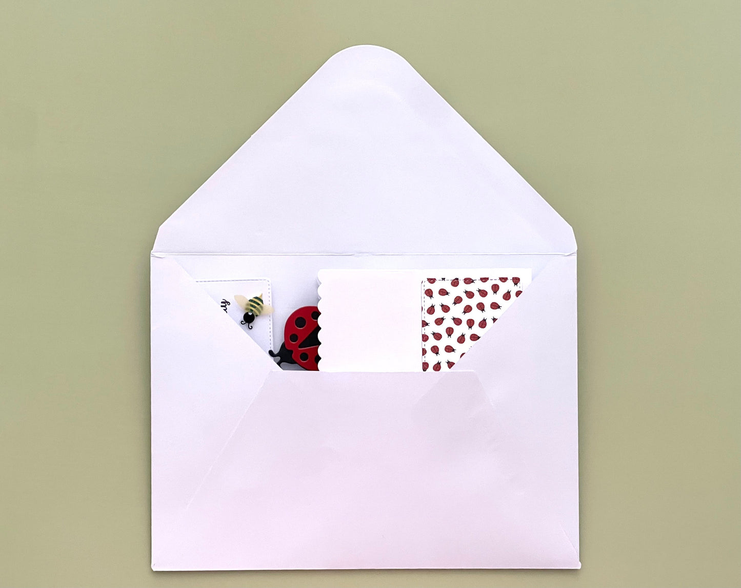 White envelope with a card featuring a ladybug design on a green background
