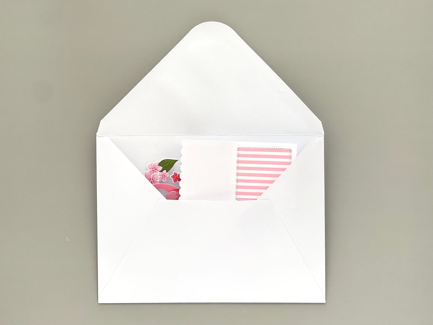 White envelope with floral design on the flap and striped pattern inside, on a beige background