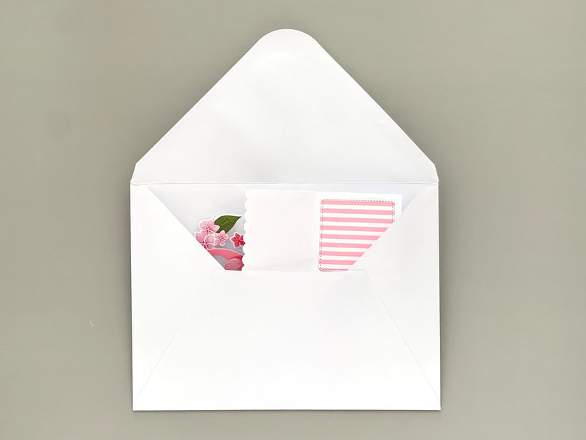 White envelope with floral design on the flap and striped pattern inside, on a beige background