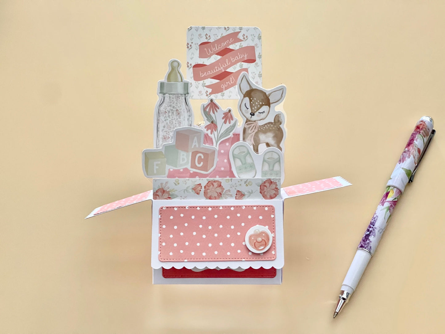 Decorative baby card with a pen on a beige background