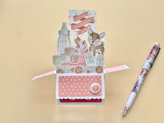 Decorative baby card with a pen on a beige background
