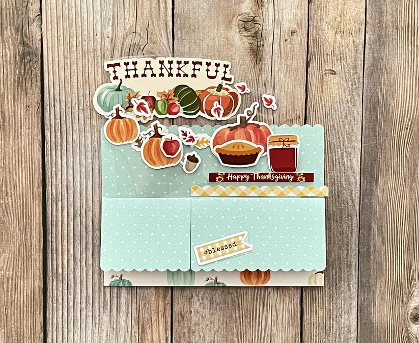 Thanksgiving-themed card with pumpkins, pies, and other fall elements on a wooden background.