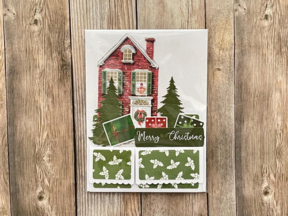 Christmas-themed card with a house and trees on a wooden surface