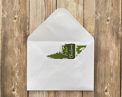 White envelope with a green Christmas card on a wooden surface