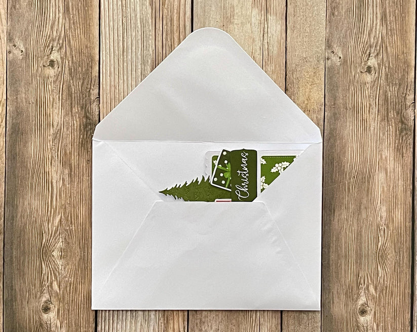 White envelope with a green Christmas card on a wooden surface