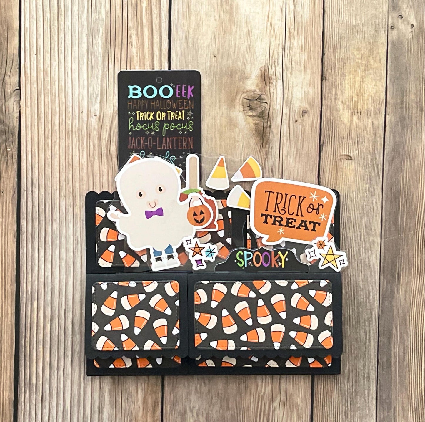 Halloween-themed card with ghost, pumpkin, and candy corn designs on a wooden surface