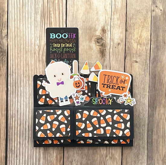 Halloween-themed card with ghost, pumpkin, and candy corn designs on a wooden surface