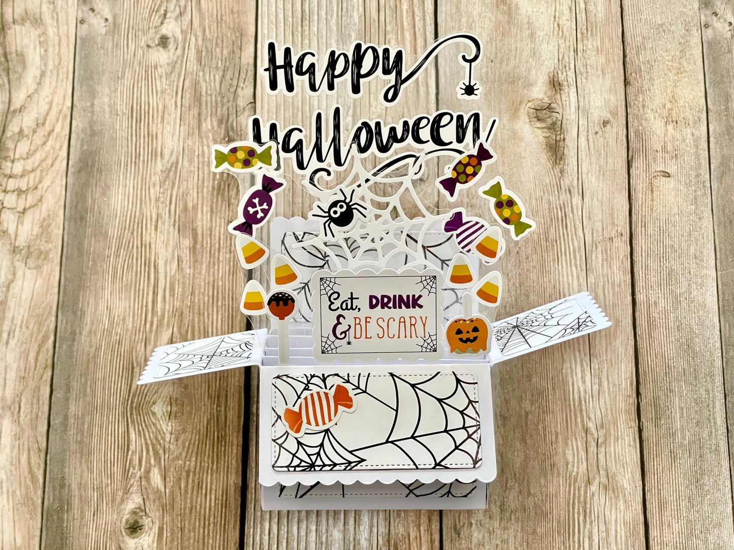 Halloween-themed pop-up card with candy-themed elements on a wooden surface