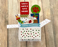 Christmas-themed card with cat illustrations and text on a wooden surface