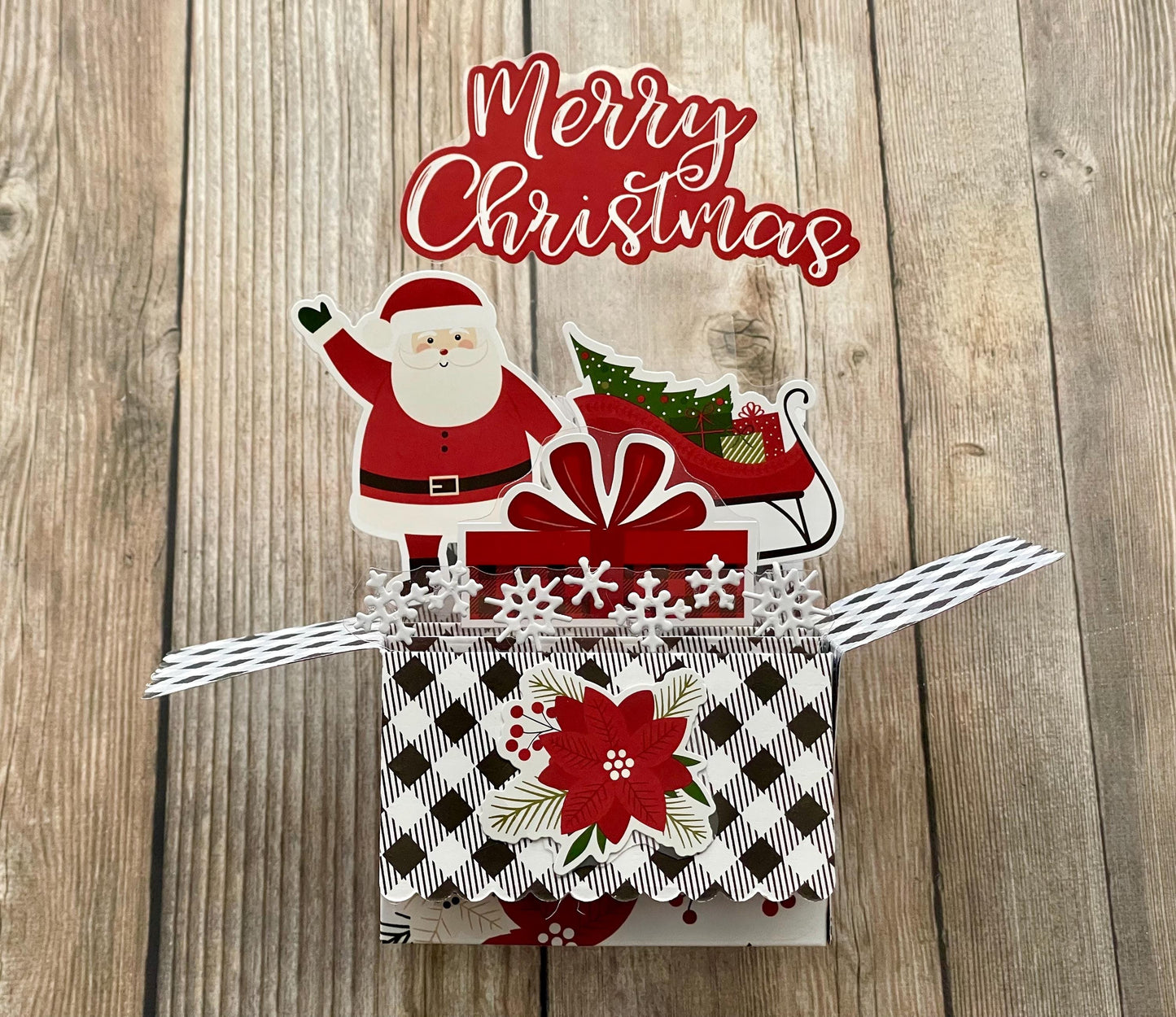 Christmas-themed pop-up card with Santa Claus and sleigh on a wooden background