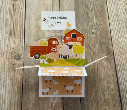 Pop-up birthday card with farm-themed design on a wooden surface