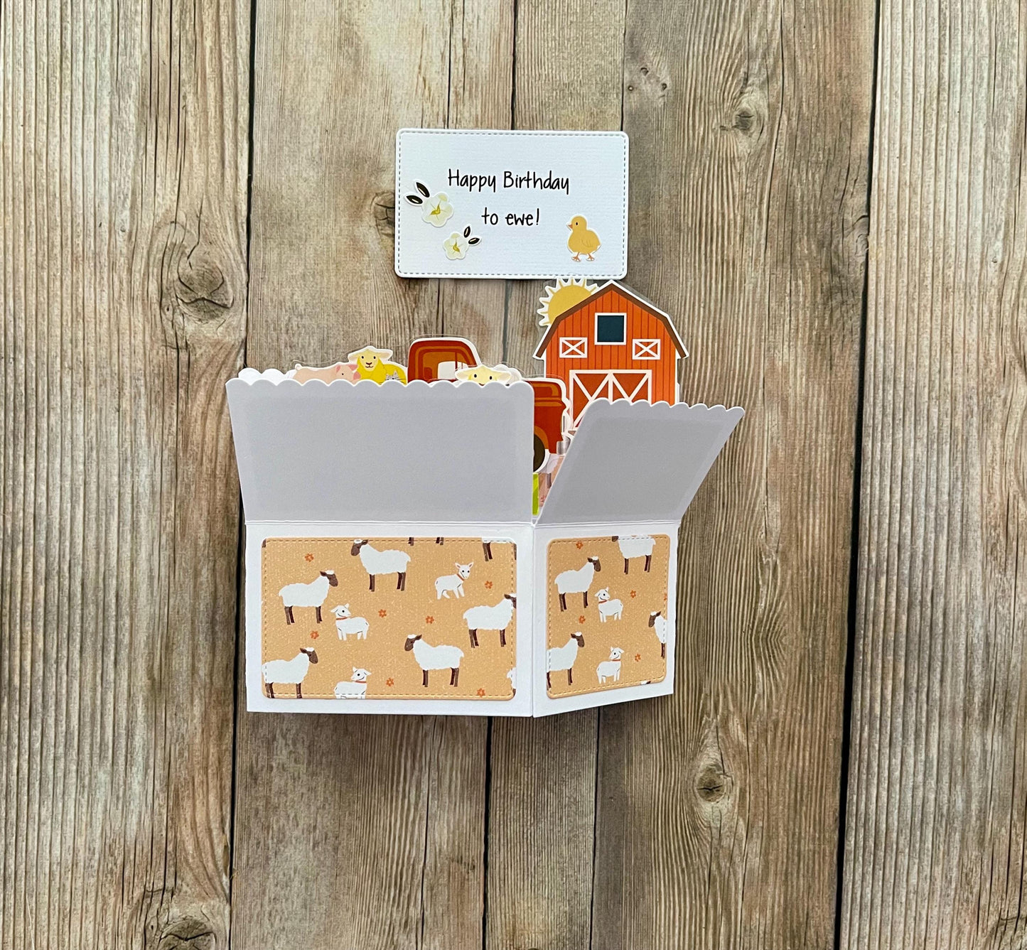 Fold-out card with farm-themed design on a wooden surface