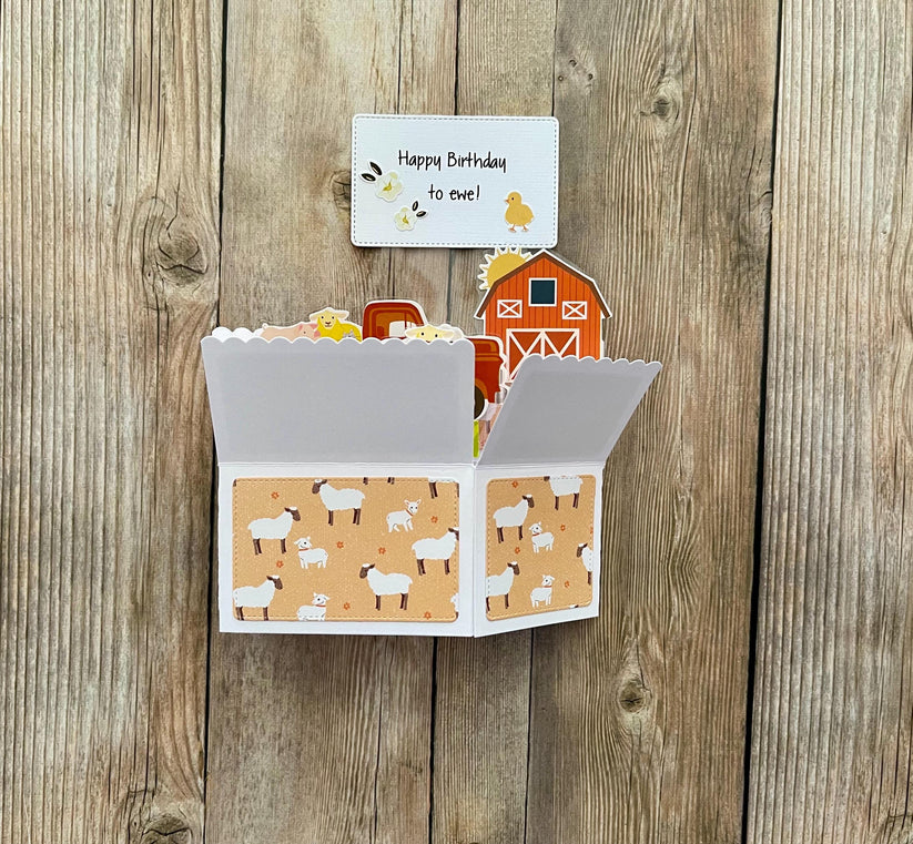 Fold-out card with farm-themed design on a wooden surface