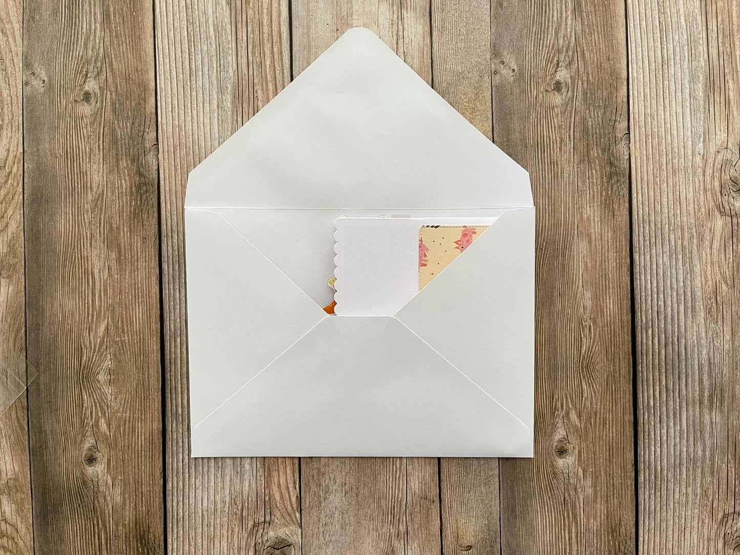 White envelope with a card inside on a wooden surface