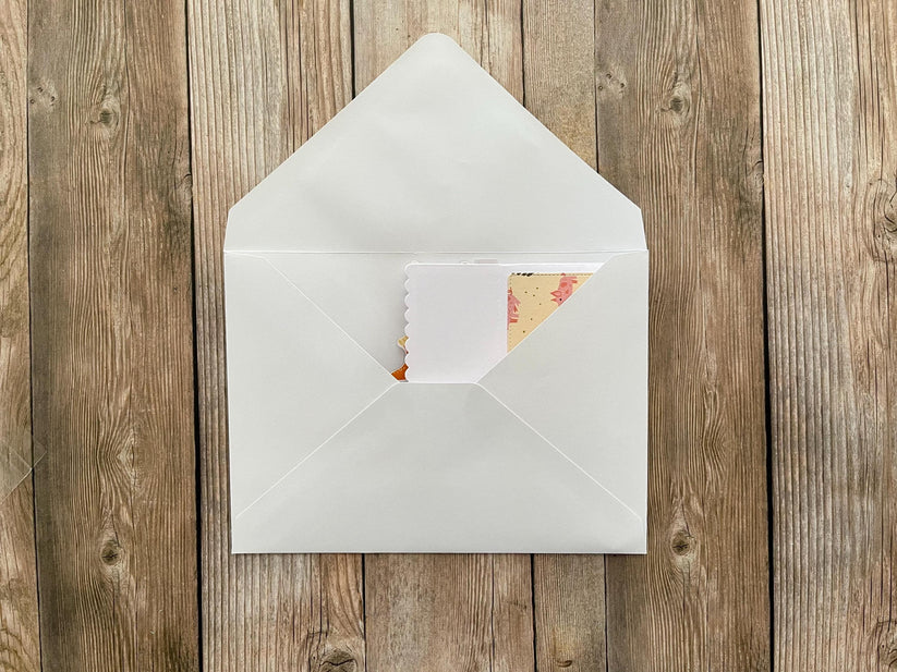 White envelope with a card inside on a wooden surface