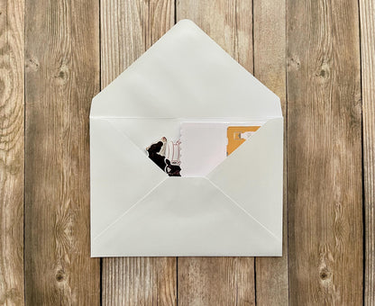 White envelope with a photo of a person on a chair inside, on a wooden surface