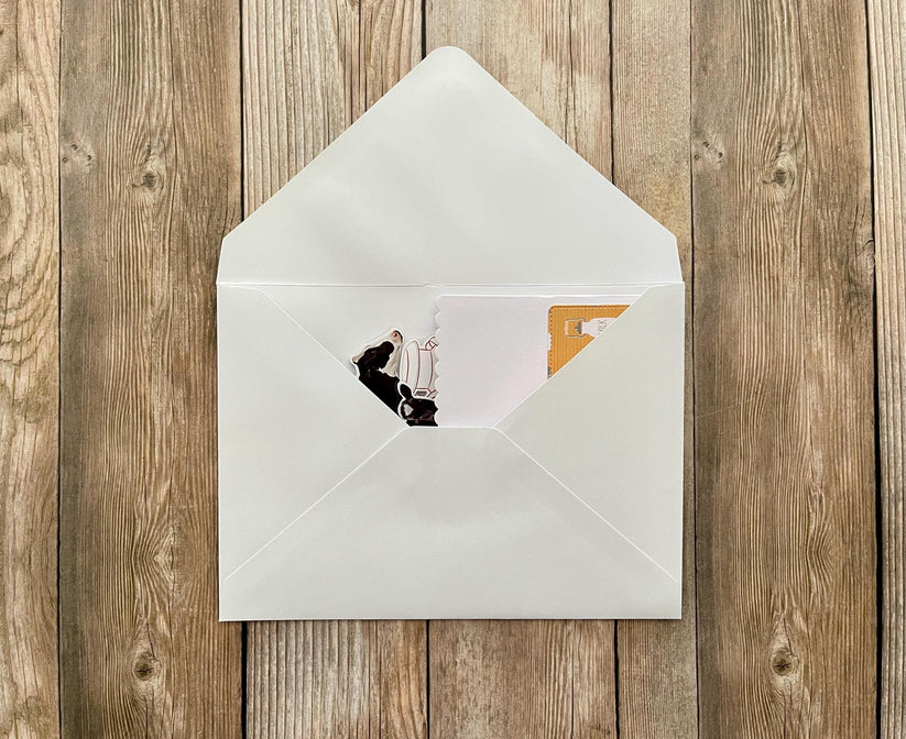 White envelope with a photo of a person on a chair inside, on a wooden surface