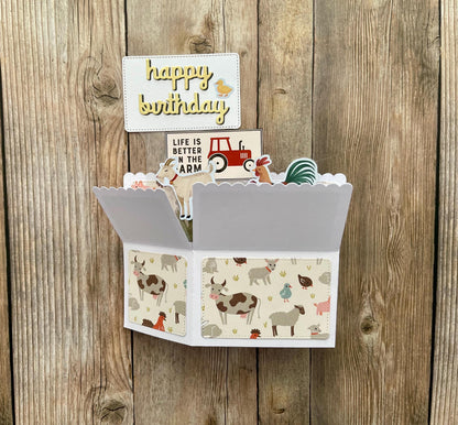 Birthday card with farm-themed design and small figurines on a wooden background